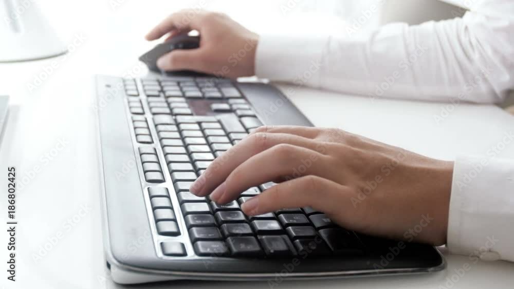 Closeup video of young businesswoman using computer mouse and typing on keyboard at office Closeup video of young businesswoman using computer mouse and typing on keyboard at office