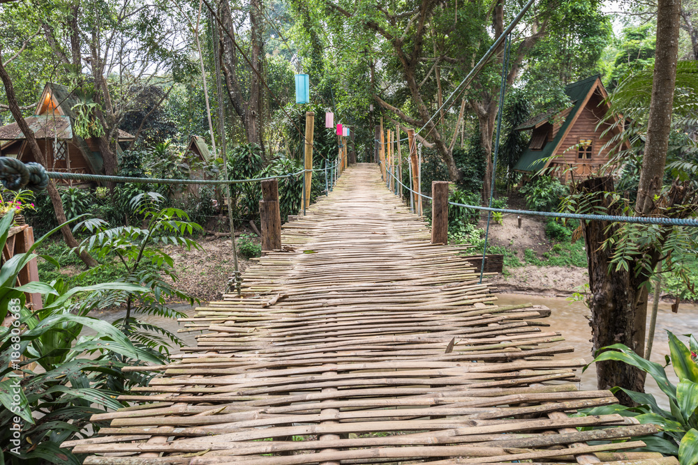 Obraz premium bamboo suspension bridge spanning the creek with house in the garden