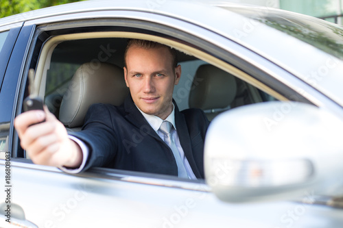 Businessman holding key inside car with smiling. Man with transportation concapt. Man Driving car to go to Office.