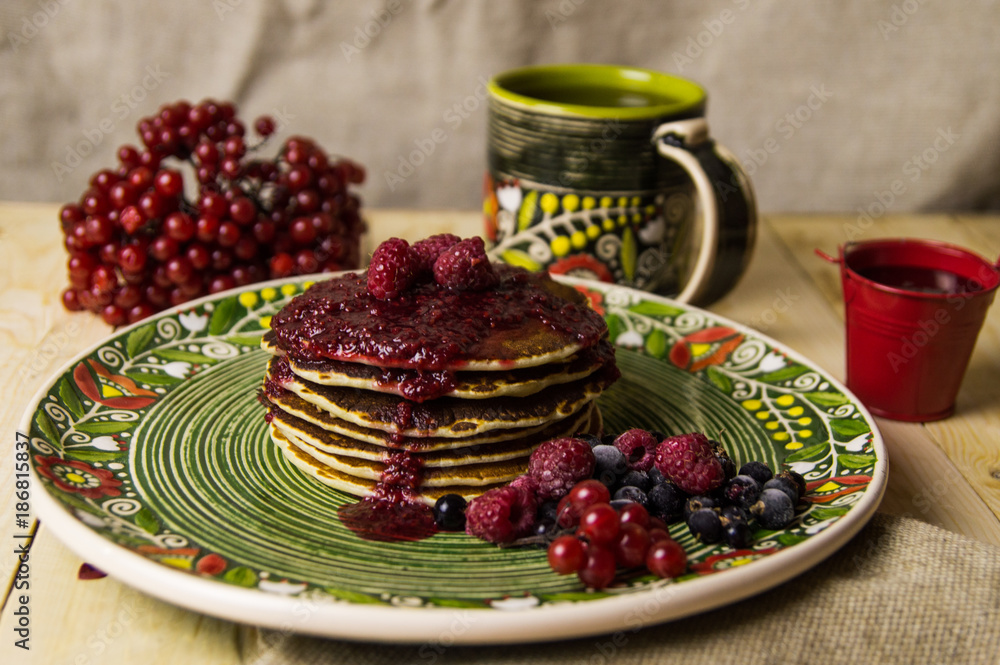 A pancake on the Christmas table with tea and raspberry jam A pancake on the Christmas table with tea and raspberry jam