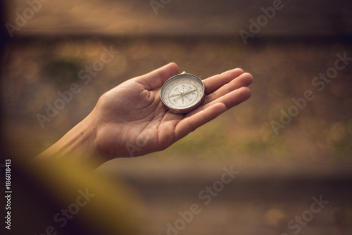 Compass in the hand with background of green nature.