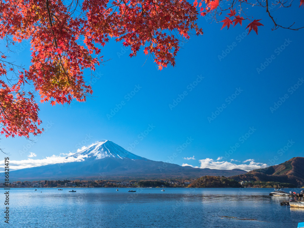 Fuji mountain with red maple and the fisherman on the boat in the lake when autumn leaf season of Japan in coming.