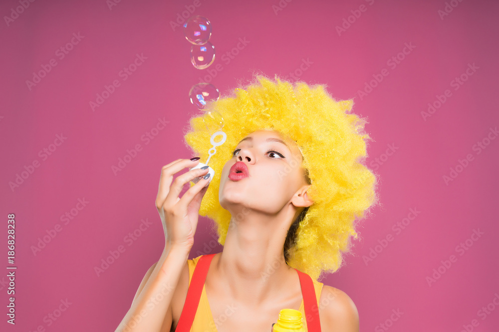A funny girl in a wig blows bubbles. Clown Stock Photo Adobe Stock