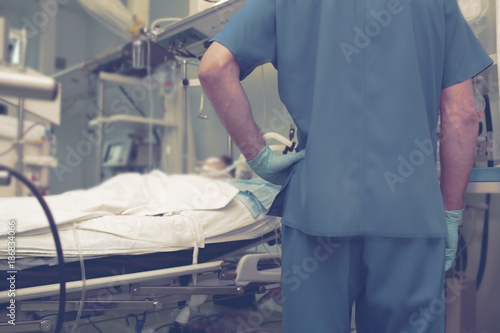 Fotografi Male doctor looking to the patient in the bed