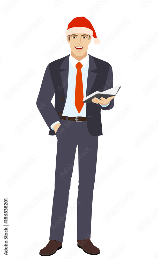 Businessman in Santa hat with hand in pocket holding book Businessman in Santa hat with hand in pocket holding book