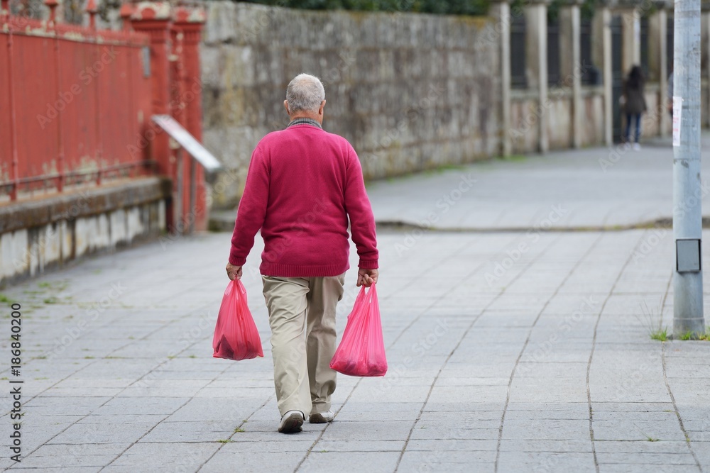 elderly man with shopping bags walking down the street