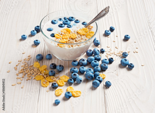 Bowl of homemade yogurt with muesli and fresh blueberry on wooden table. Fresh yogurt. Healthy food concept. High resolution product.