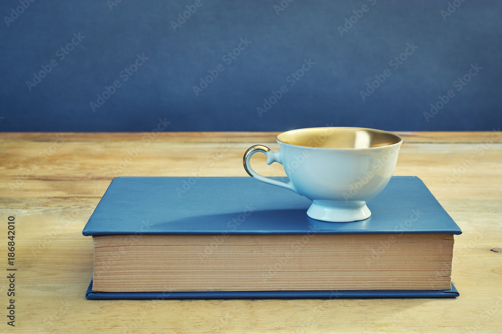 cup on blue book on grunge wooden table cup on blue book on grunge wooden table
