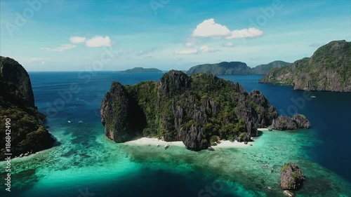 Aerial view flying over amazing white sand beach and tropical coral reef lagoon towards beautiful green mountains on Simizu island photo