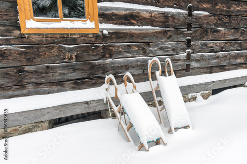 Tiefer Winter, Schlitten lehnen an einer Hüttenwand, Hüttenzauber