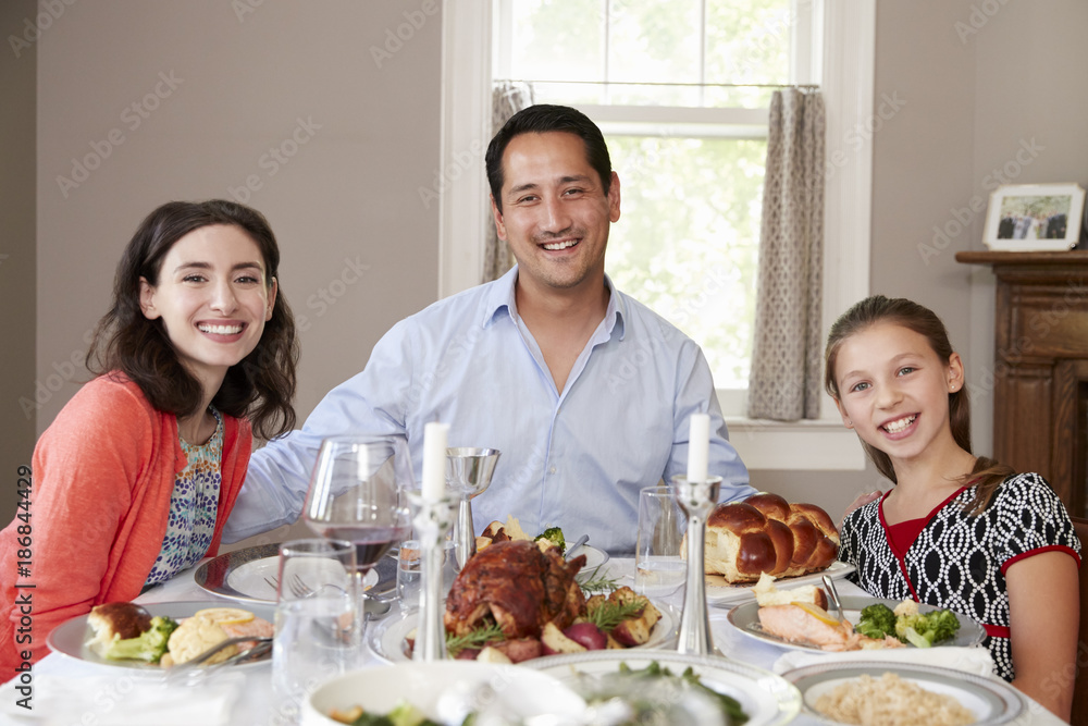 Jewish family at Shabbat dinner table smiling to camera