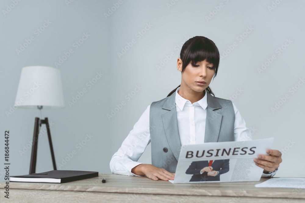 businesswoman reading newspaper in office on gray businesswoman reading newspaper in office on gray
