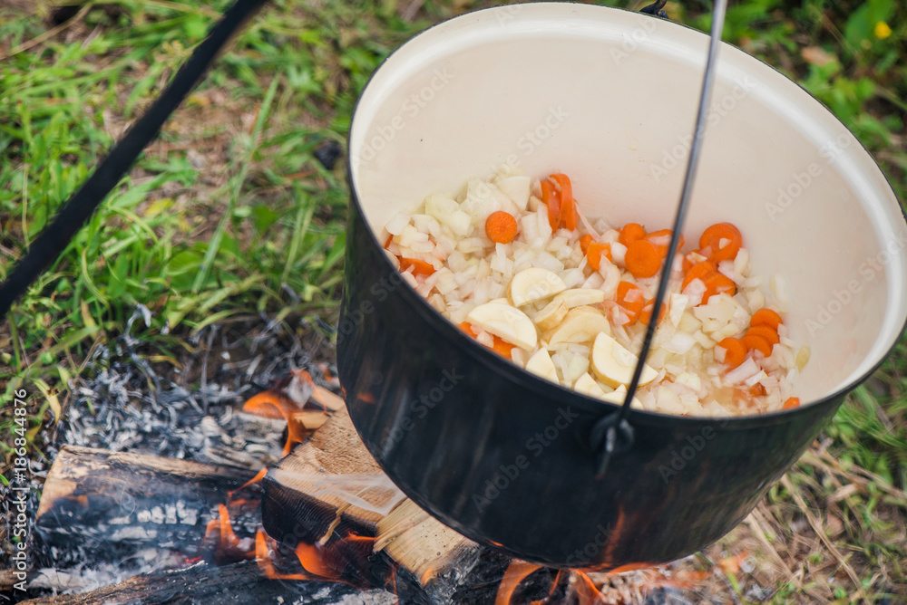Boiling, hot goulash soup with meat, paprika, potatoes, onion, carrots is the traditional dish of Hungarian cuisine. Meat stew being prepared in crock pot on open fire. Picnic at the weekend in nature Boiling, hot goulash soup with meat, paprika, potatoes, onion, carrots is the traditional dish of Hungarian cuisine. Meat stew being prepared in crock pot on open fire. Picnic at the weekend in nature