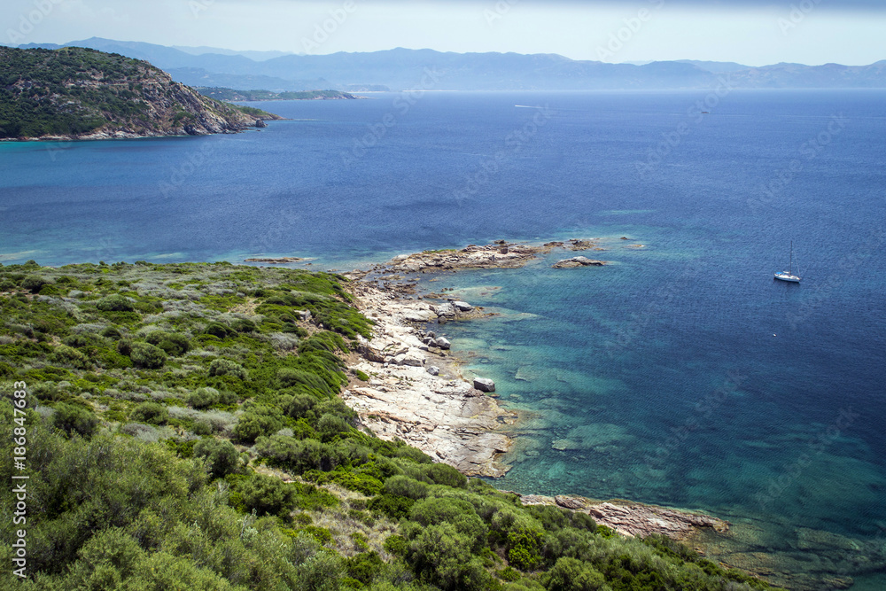 green coastline, azure sea between rocks in the mountains on the island of Corsica