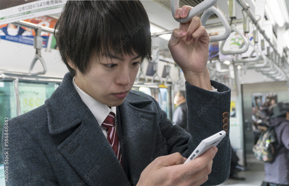 Φωτογραφία 電車内でスマホを見るビジネスマン
