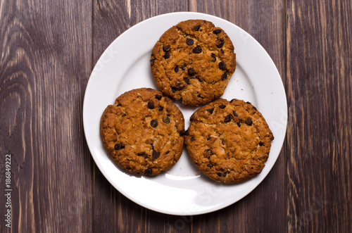 Homemade oatmeal cookies on a white plate. Wooden background