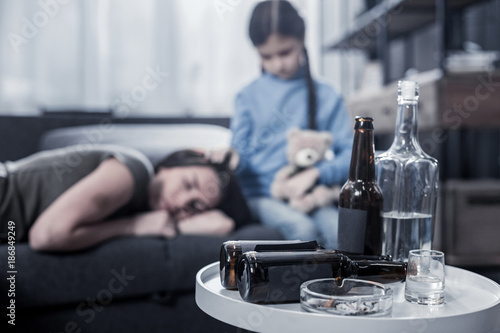 Alcohol addiction. Selective focus of a coffee table with empty beer bottles standing on it