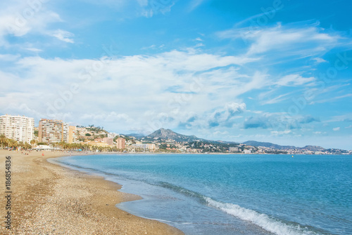 Panoramic aerial top view to Malaga city and La Malagueta beach, hotels, resorts, buildings and wavy Mediterranean sea on sunny day, Andalusia, Spain. Winter relax vacation by the sea concept.