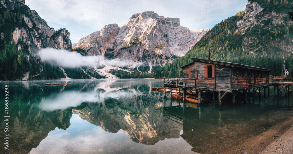 Fototapeta Panoramic view of Braies Lake with the hut and boats in Dolomites mountains and Seekofel in the morning, Sudtirol, Italy