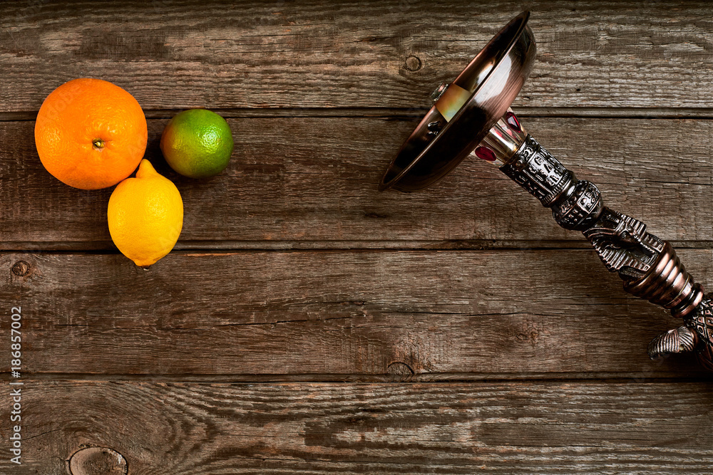 Dismantled part of hookah on a wooden background with lime fruit Dismantled part of hookah on a wooden background with lime fruit