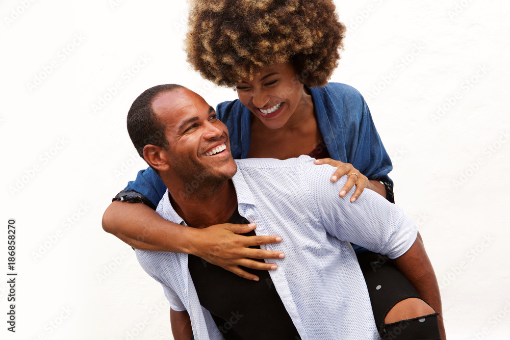 fun couple smiling in embrace by white wall fun couple smiling in embrace by white wall