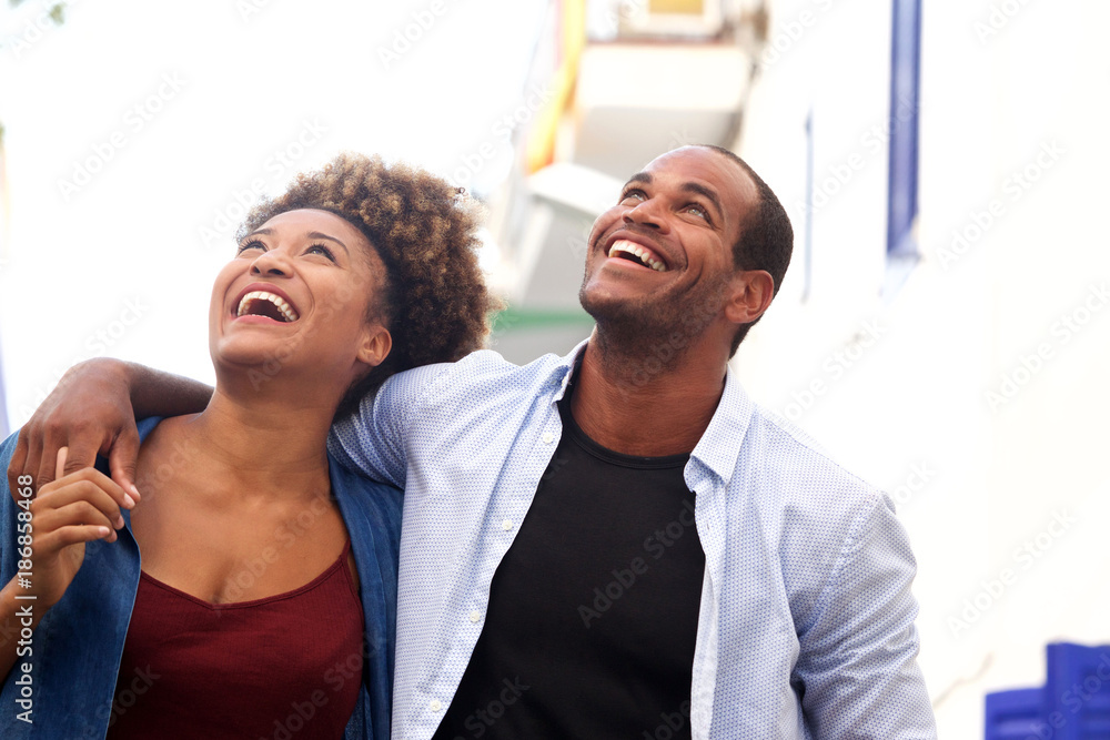 Laughing couple walking together in embrace on date