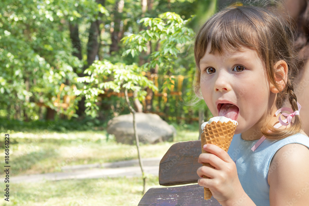 Cute little girl eating ice-cream in the city park on a summer sunny day. Portrait little girl with copy space. Cute little girl eating ice-cream in the city park on a summer sunny day. Portrait little girl with copy space.