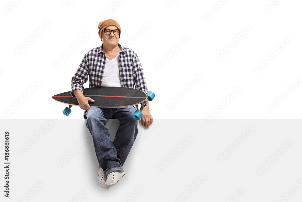 Old hipster with a longboard sitting on a panel Old hipster with a longboard sitting on a panel