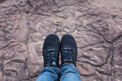 Top view of female wearing fashional black sneaker and blue jeans on stone floor backgrounds