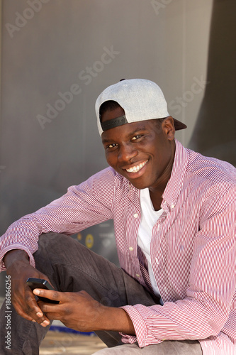 smiling african man in cap sitting with a mobile phone