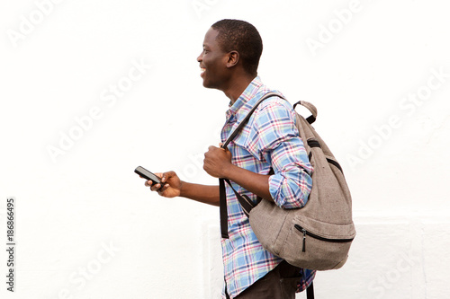 male student walking outside with bag and mobile phone