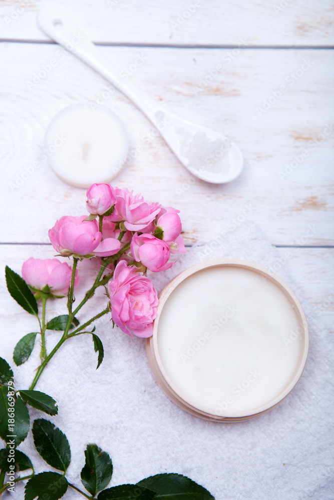 organic cosmetic with rose and pot of moisturizing face cream on white background