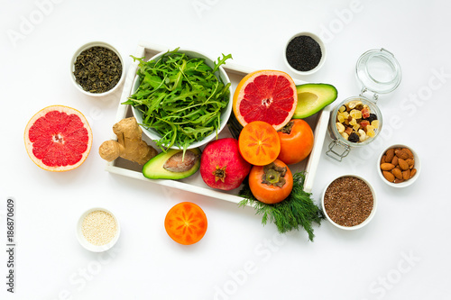 Healthy food in wooden tray  fruits  vegetables  seeds and greens on white background. Flat lay. Top view