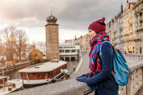 Woman tourist in a coat with a backpack travels in the Prague city