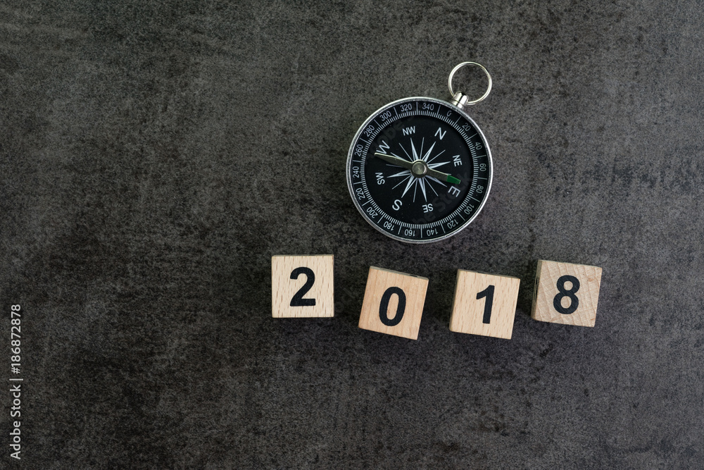 Year 2018 prediction or direction concept with compass and wooden block number 2018 on dark black background Year 2018 prediction or direction concept with compass and wooden block number 2018 on dark black background