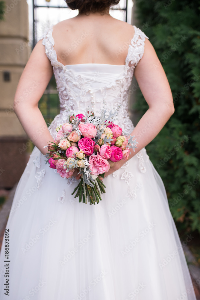 Bride holds in her hands wedding bouquet with pink roses Bride holds in her hands wedding bouquet with pink roses