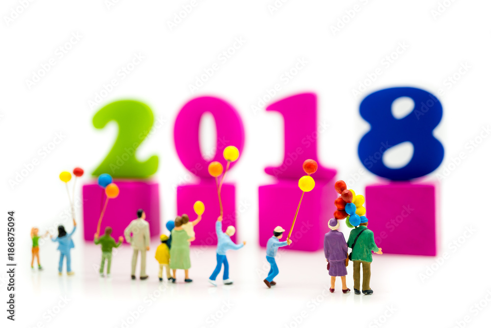 Miniature people standing with balloon and colorful year 2018 wooden block using as family relationship and New Year concept