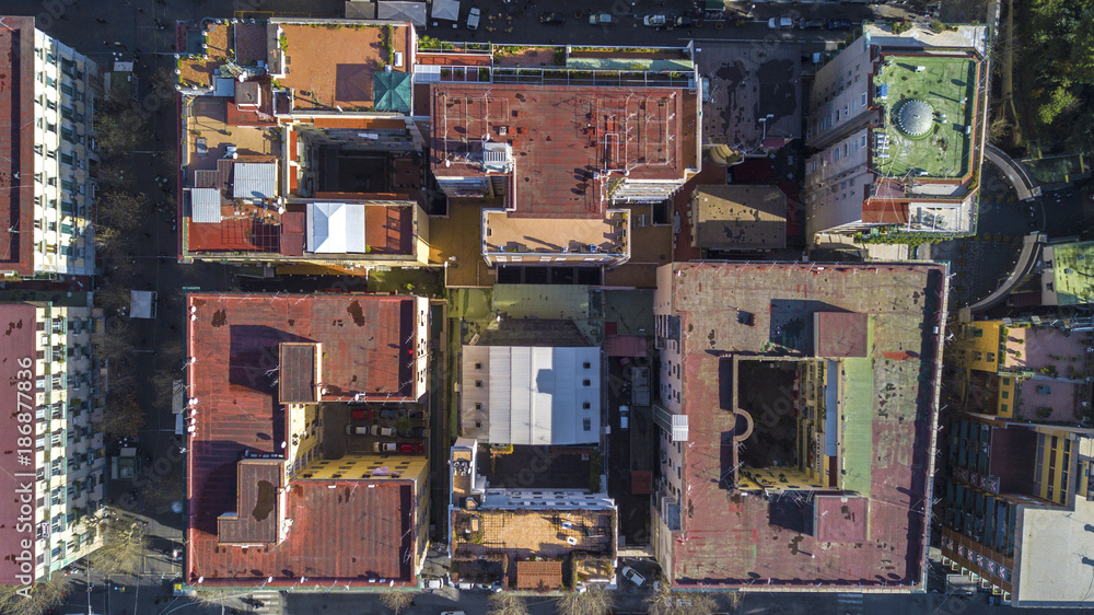 Perpendicular aerial view of a group of buildings in the Vomero district in Naples, Italy. All the roofs are walkable and full of antennas and TV dishes. down the streets lit by the sun.