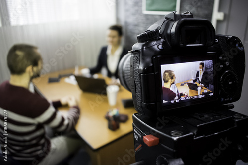 camera on the set of a business meeting between a man and a woman