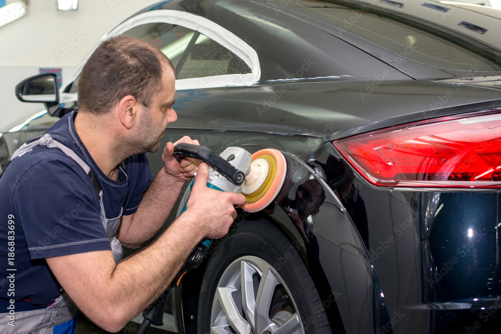 A man polishes a black car with a polisher A man polishes a black car with a polisher