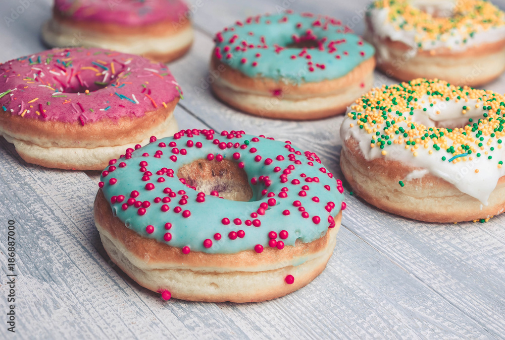 Donuts with colorful icing on a wooden background. Donuts with colorful icing on a wooden background.