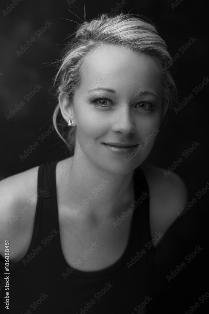 Beautiful fit and healthy blond woman portrait in black top in dark with selective lighting artistic conversion Beautiful fit and healthy blond woman portrait in black top in dark with selective lighting artistic conversion