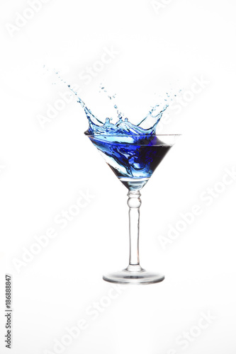 Martini glass with blue water splash in it isolated on white background