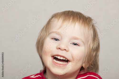 cheerful blond boy in red clothes smiling