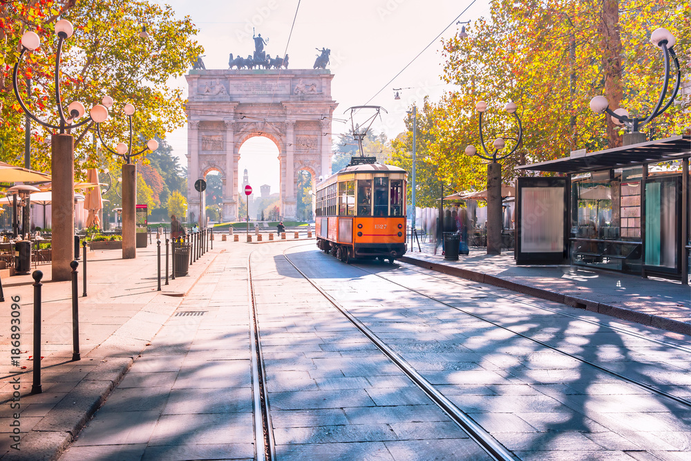 Naklejka premium Słynny zabytkowy tramwaj w centrum Starego Miasta w Mediolanie w słoneczny dzień, Lombardia, Włochy. Łuk Pokoju, czyli Arco della Pace w tle.