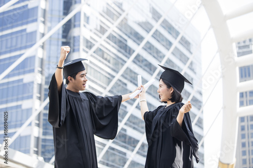 Young Asian Students wearing Graduation hat and gown at University, People with Graduation Concept.