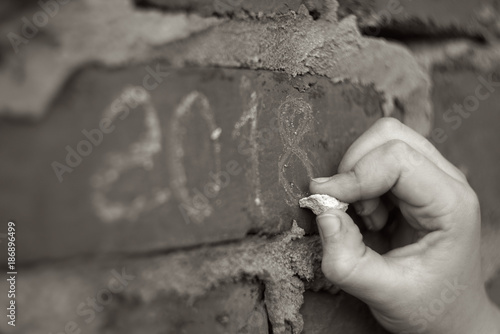 A hand writing 2018 on the brick wall. black and white