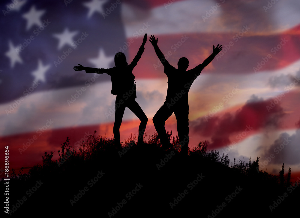 Two people against the American flag Full length silhouette of a happy couple stand together on top of a mountain with their hands up, Man and woman on top of a mountain of freedom.Democracy