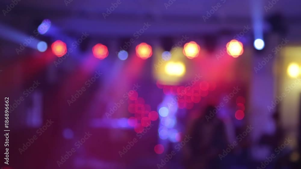 Background of the dance is blurred people dancing in a nightclub. Blue and purple colors Background of the dance is blurred people dancing in a nightclub. Blue and purple colors