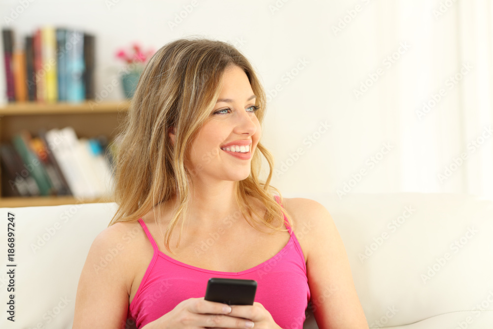 Girl in pink holding a smart phone looking at side Girl in pink holding a smart phone looking at side